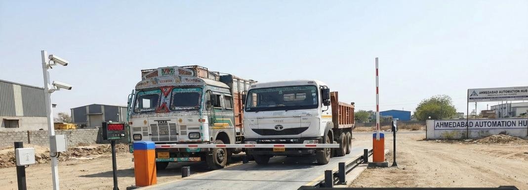 Commercial trucks on industrial weighbridge platform with automated gate and CCTV
